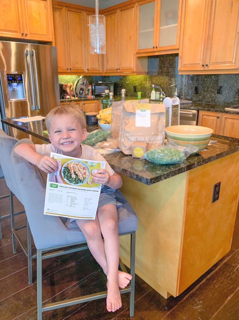 Braeden holding the recipe card for a Green Chef meal